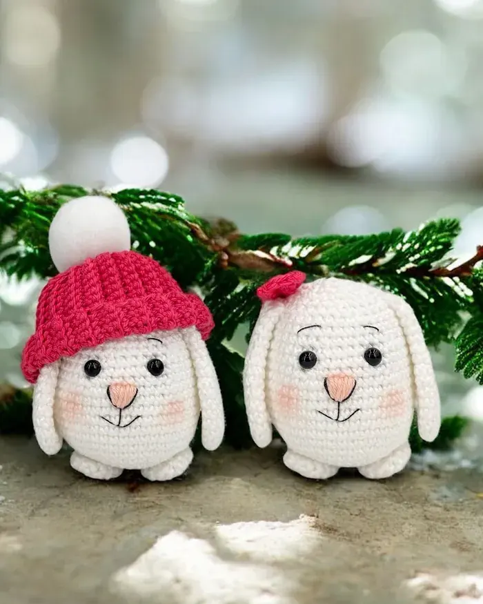 Deux lapins blancs de Féerie d’hiver, l’un coiffé d’un bonnet rouge